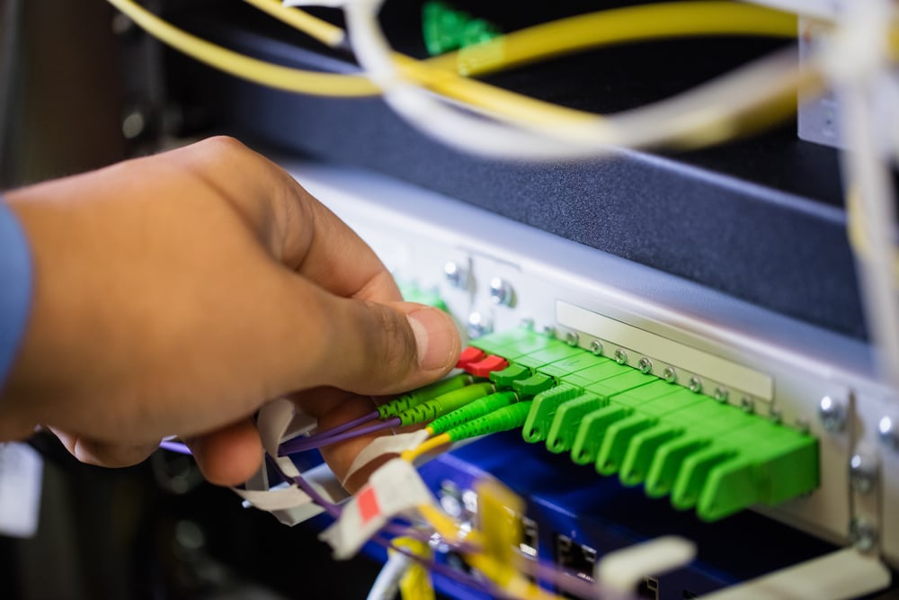 Close-Up of technician plugging patch cable in a rack mounted server in server room